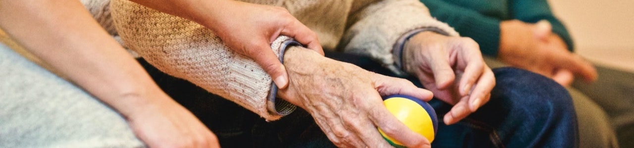 Hand holding elderly man's hand at Sea to Sky Hospice Society