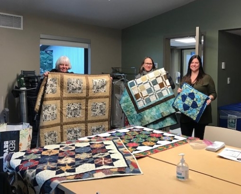 Anne Babuin, Diana Gunstone and Carlee Baker show off the beautiful new quilts.